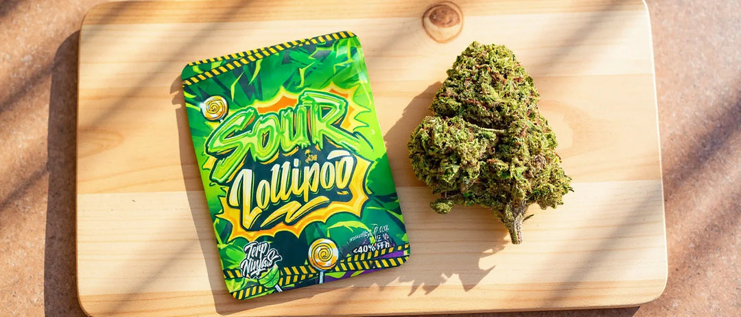 Superior Blend Erfahrungen: Beutel Sour Lollipop und Blüte auf hellem Holzbrett