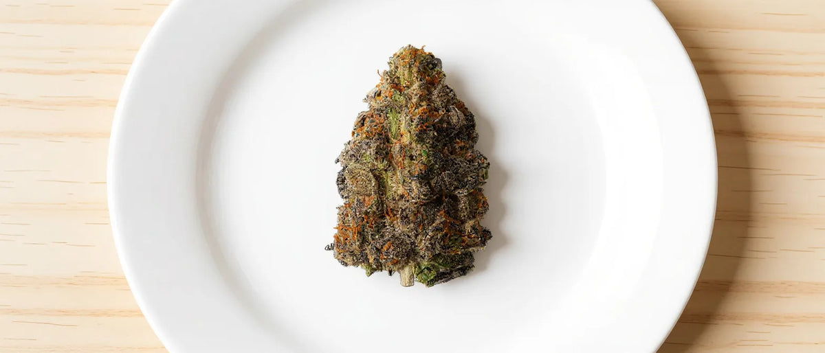 THC-Liquid: Hanfblüte auf weißem Teller, heller Holztisch